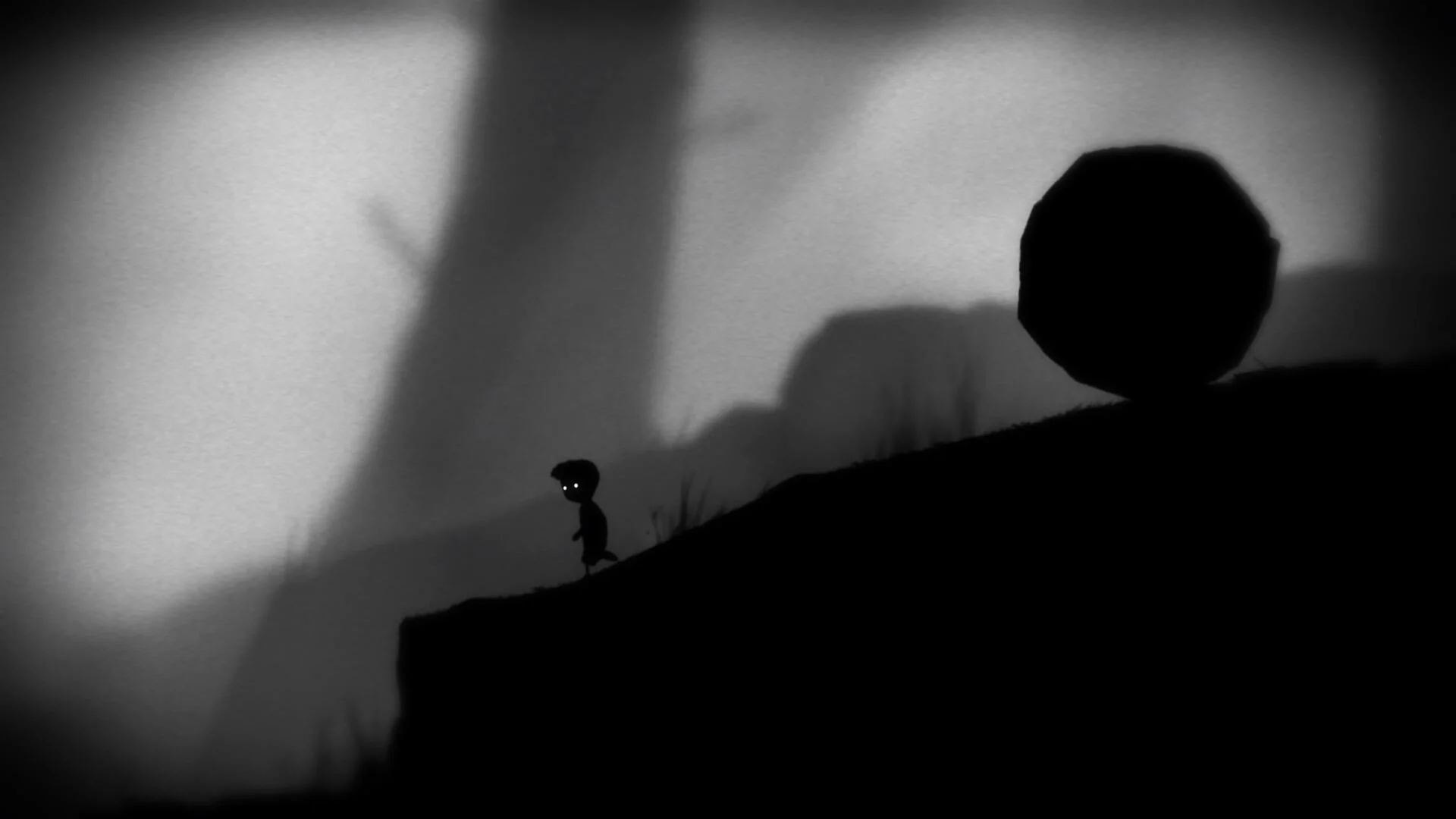 Мальчик идет перед огромным валуном в игре Limbo