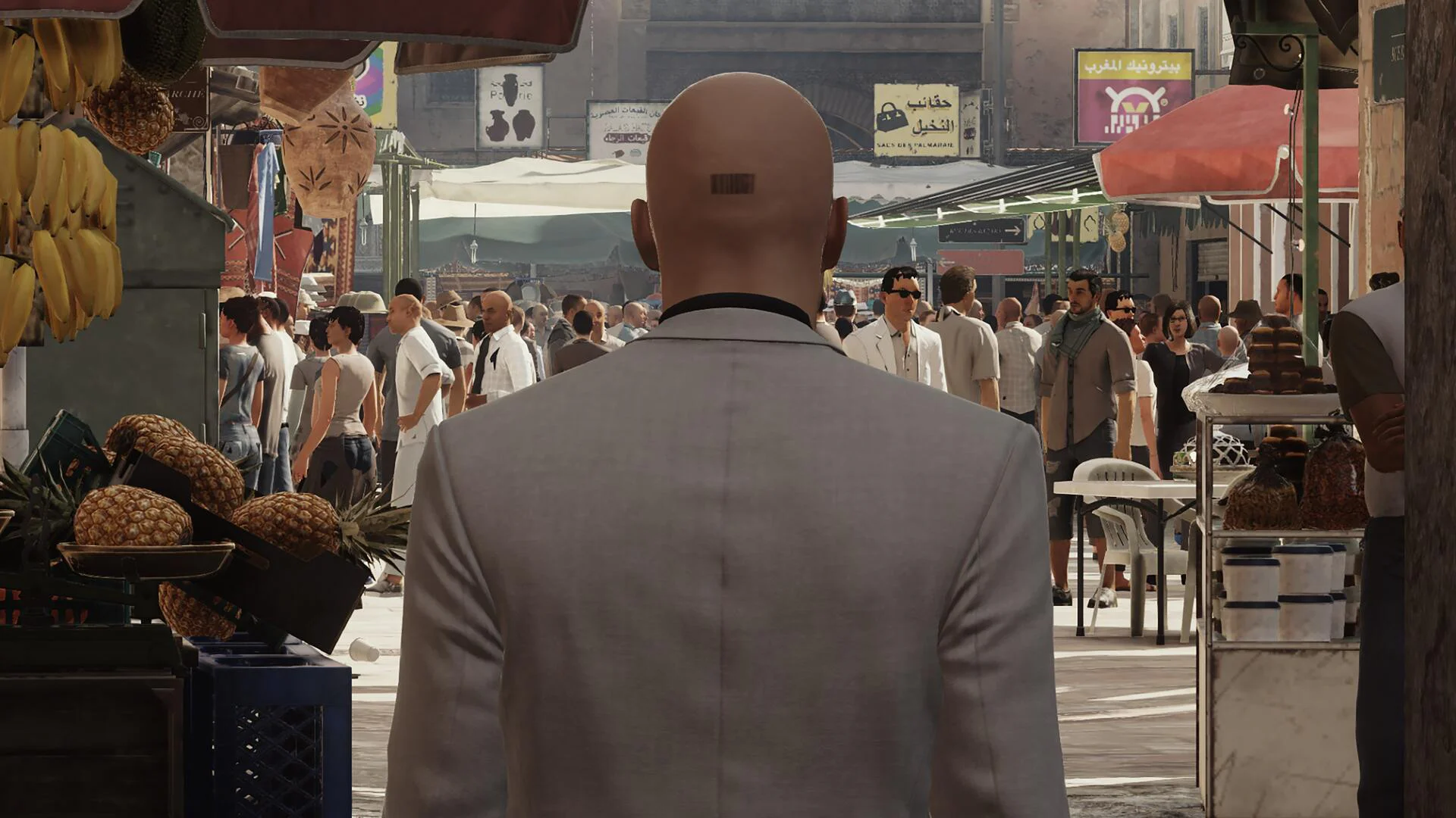 Агент 47 в светлом костюме стоит на оживленном восточном рынке, Hitman.