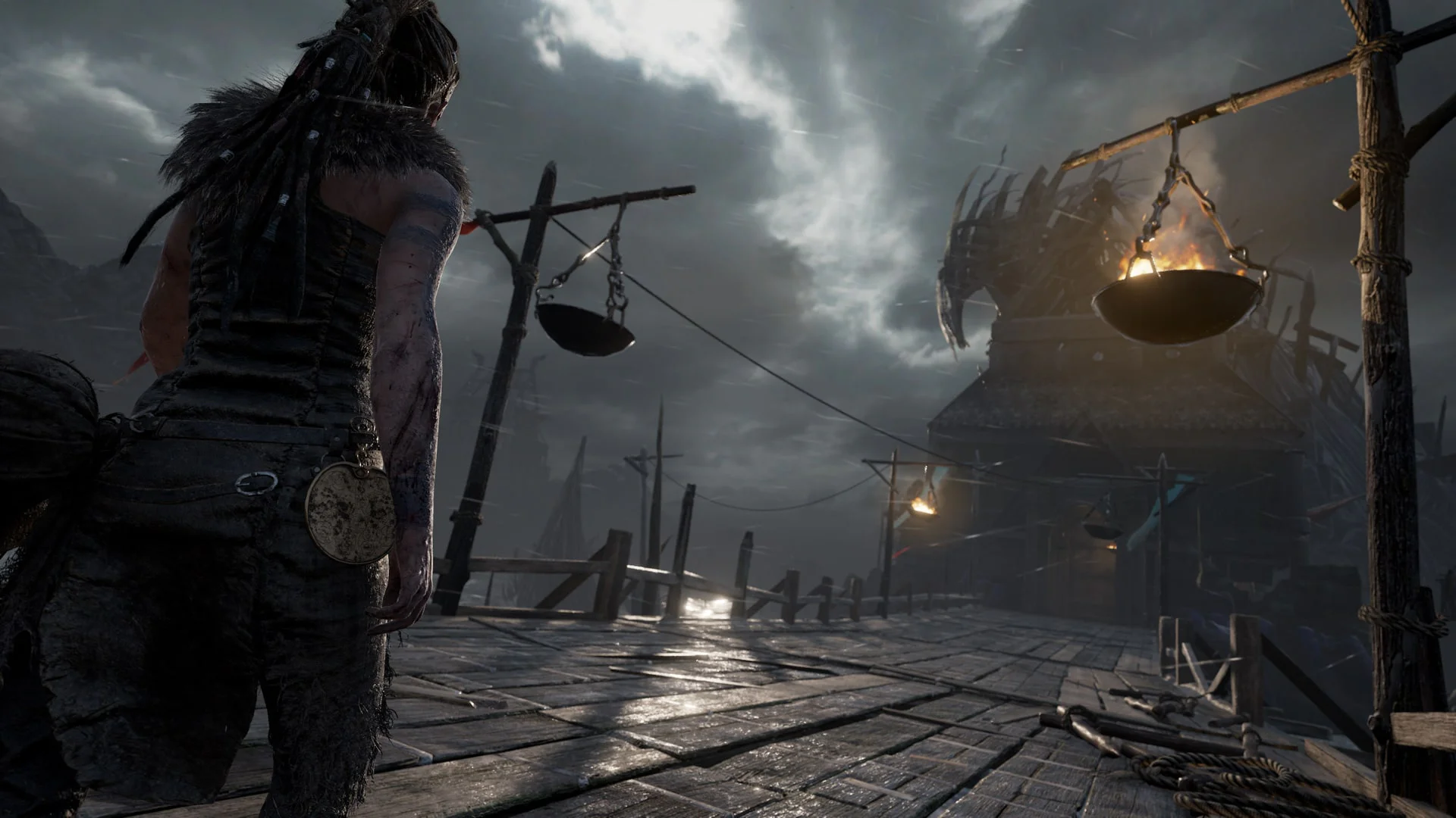 Сенуа стоит на мосту перед мрачной крепостью в Hellblade: Senua’s Sacrifice